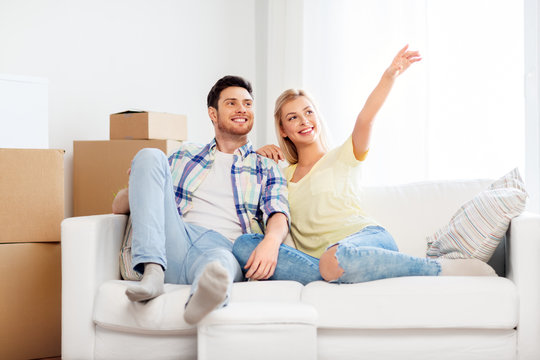 moving, people, repair and real estate concept - happy couple with big cardboard boxes on sofa at new home