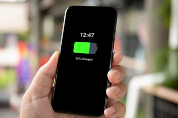man hand holding phone with charged battery on the screen