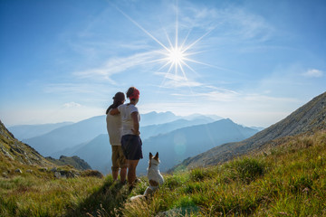 Fototapeta na wymiar Couple with dog admiring the view from the top of a mountain