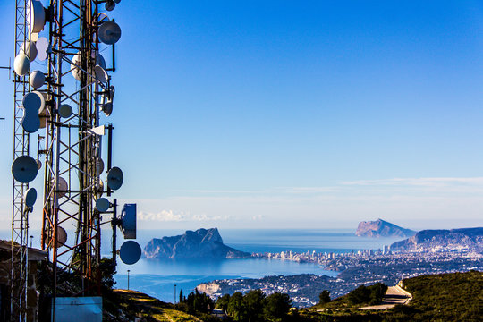 Telecommunication antennas in the Cumbre del Sol mountain, also known as "Puig Llorenca" in Benitatxell, Spain. Ifach Rock and Calpe city is in the background.