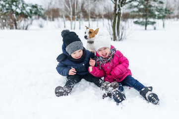 Fototapeta na wymiar Children playing with Jack Russell terrier puppy in the park in the winter in the snow