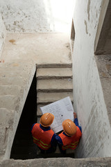 Civil engineers analyzing construction plan when walking up the stairs, view from above