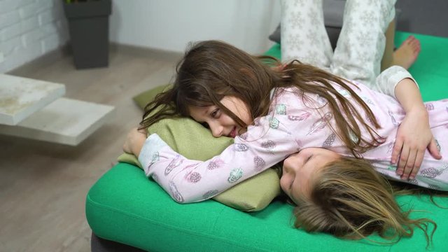 two kids in pajamas fighting on sofa