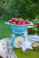 Heap of strawberry fruits lying on blue vintage kitchen scale.