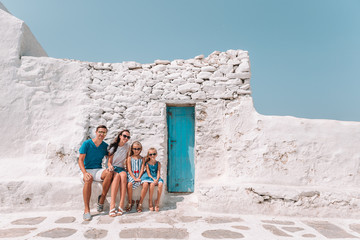 Parents and kids at street of typical greek traditional village on Mykonos Island, in Greece
