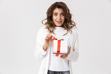 Portrait of optimistic woman in casual clothes holding present box, isolated over white background