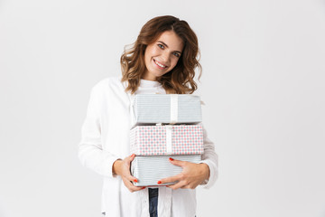 Image of beautiful woman in casual clothes holding present boxes, isolated over white background