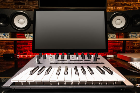 home studio. recording equipment, computer monitor, midi keyboard, analog synthesizer, studio loudspeakers monitor