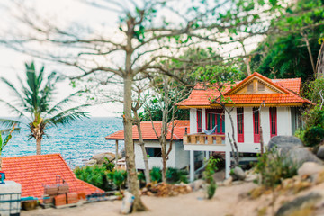 Obraz premium Bungalow na tropikalnej wyspie w Tajlandii. Dom nad oceanem z czerwonym dachem. Hamak wiszący na balkonie. Ocean w tle. Nakręcony obiektywem z funkcją tilt shift