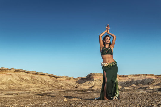 Woman dancing to the famous belly dance with natural sunset light, in the Namibe Desert with canyons. Africa. Angola.