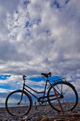 Fototapeta premium Vintage bicycle against the blue sky with clouds and sea.