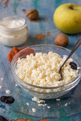 Natural and healthy food. Fresh homemade cottage cheese, a small jar of sour cream, raisins, dried apricots and apples on an old wooden table. 