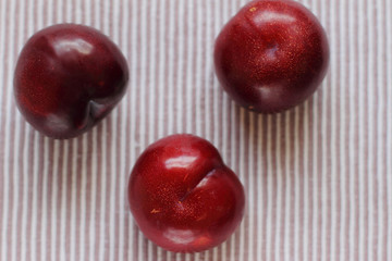 three natural fresh plums on table