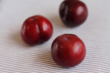 three natural fresh plums on table