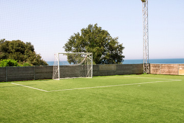 Fototapeta premium Soccer goal door with white net. Football goal at soccer field with green grass and sport stadium on campus, bleachers, white line and soccer field corner. Sports elements, equipment and environment.