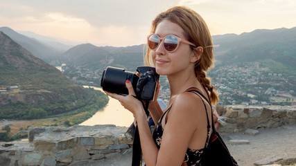 Female photographer, taking pictures of mountain landscape at sunset