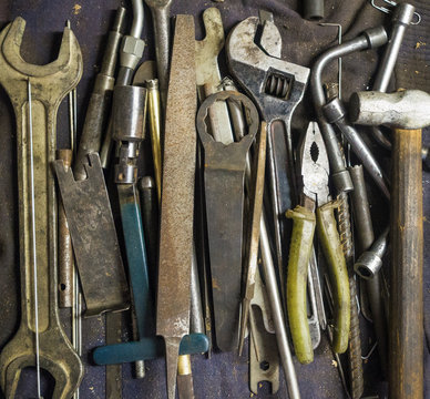 Tools For Car And Engine Maintanance And Repair, Laying On The Garage Workbench - Pliers, Wrenches, Files, Hammer, Adjustable Wrench, Socket Wrenches.