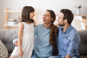 Happy family of three laughing talking playing, little kid daughter having fun communicating with...