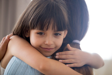 Cute little child girl embracing loving mother, happy kid hugging mom holding tight cuddling,...