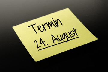 Termin 24. August - gelber Notizzettel dunkler Hintergrund