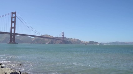 young girl traveler sightseeing beautiful view of golden gate bridge in san francisco california usa. boats ships driving on sea ocean under blue sky in background. wind blowing in summer sunny flare - Powered by Adobe