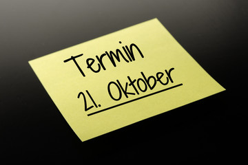 Termin 21. Oktober - gelber Notizzettel dunkler Hintergrund