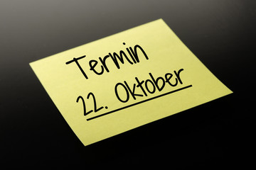 Termin 22. Oktober - gelber Notizzettel dunkler Hintergrund