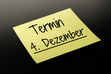 Termin 4. Dezember - gelber Notizzettel dunkler Hintergrund