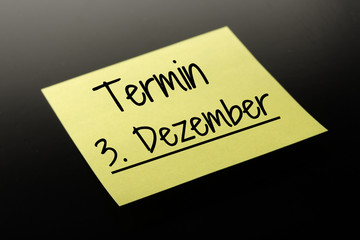 Termin 3. Dezember - gelber Notizzettel dunkler Hintergrund