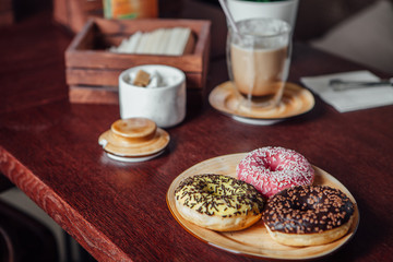 Donuts in colorful glaze are lying on a plate in a cafe