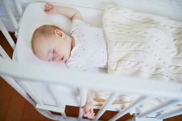 Fototapeta na wymiar Baby sleeping in co-sleeper crib attached to parents' bed