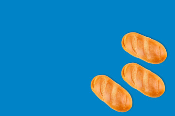 Three whole baked breads in corner on blue background with copy space for your text