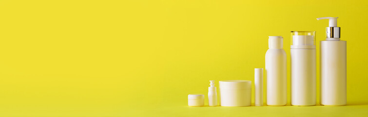 White cosmetic tubes on yellow background with copy space. Skin care, body treatment, beauty concept. Banner