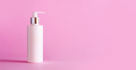White bottle of moisturizing lotion on pink background with copy space. Minimalism style. Skin care, body treatment, beauty concept