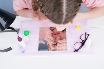 the girl, using a mirror, wears a contact lens to improve vision, using a set of items