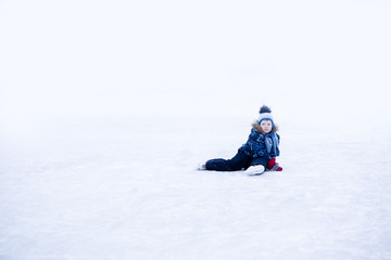 Fototapeta na wymiar funny moment - cute little boy fell on the ice skating rink