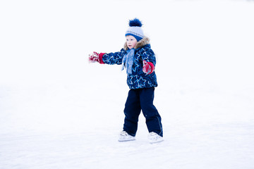 Fototapeta na wymiar active winter holiday - cute little boy skating on an ice rink
