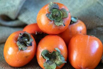 Fruits kaki en tas sur toile de jute	