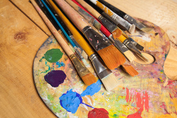 Fototapeta premium Paints, brushes and palette on the wood background. The workplace of the artist. Banner for school
