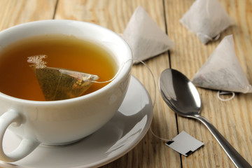 cup with tea and tea bag pyramid. close-up. on a wooden table. to make tea
