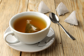 cup with tea and tea bag pyramid. close-up. on a wooden table. to make tea