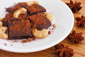 Delicious broken dark chocolate with cocoa powder and cashew nuts and star anise