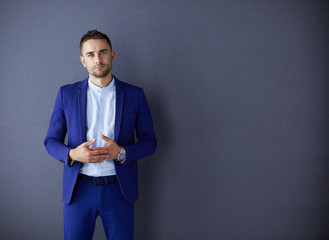 Young businessman sitting isolated on grey background.