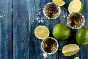 gold tequila in glass glass with salt and lime on a blue wooden background. bar. alcoholic beverages. view from above. with space for text