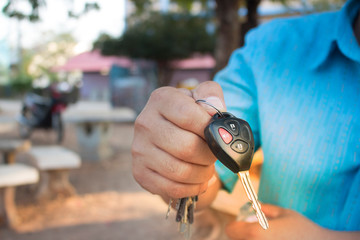 Men's hands are showing car keys with unlocking symbols and alarms.