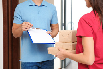 Woman receiving parcels from delivery service courier indoors, closeup