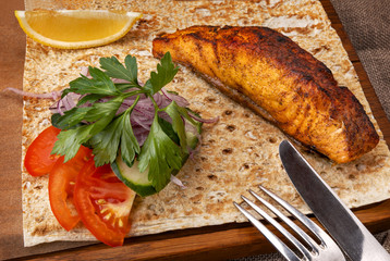 restaurant menu. grilled salmon with vegetables and lavash. knife and fork near the plate