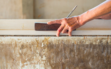The hands of the craftsmen who are working on the wood with the