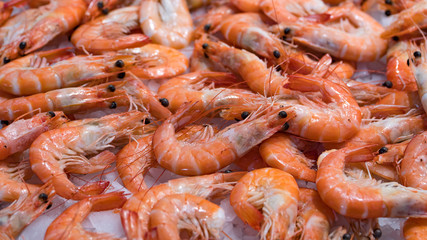 Pink fresh frozen shrimps with ice in a supermarket or fish shop. Uncooked seafood close up background. Fresh frozen prawns, delicacies, sea food concept, close up.