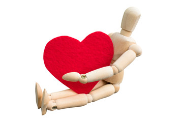 Wooden dummy hug a heart shape that made from acrylic felt fabric. Wooden puppet sitting isolated on white background. Valentine's day concept.